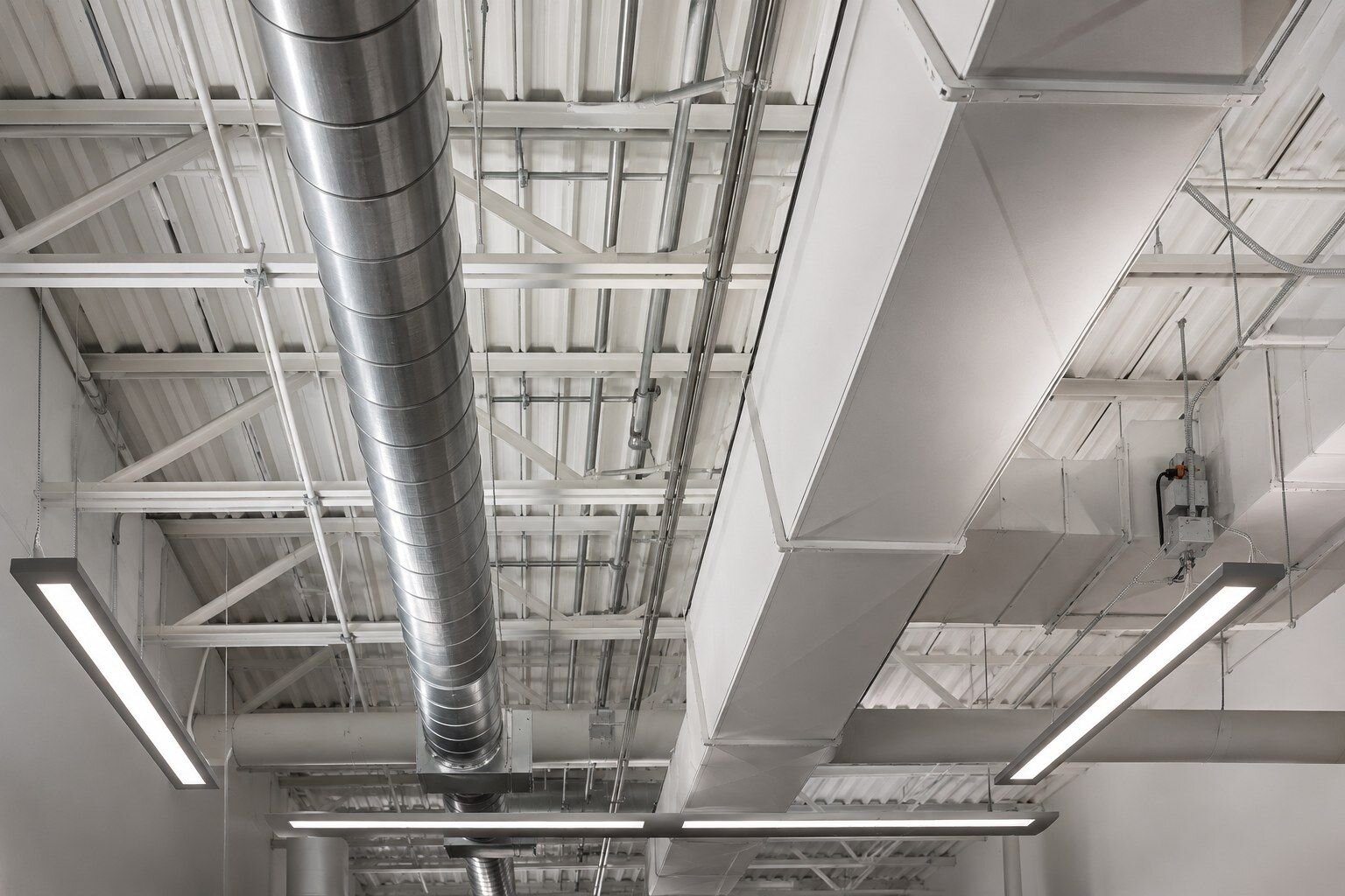 Exposed ceiling of a finished commercial fit-out with spiral duct and service runs