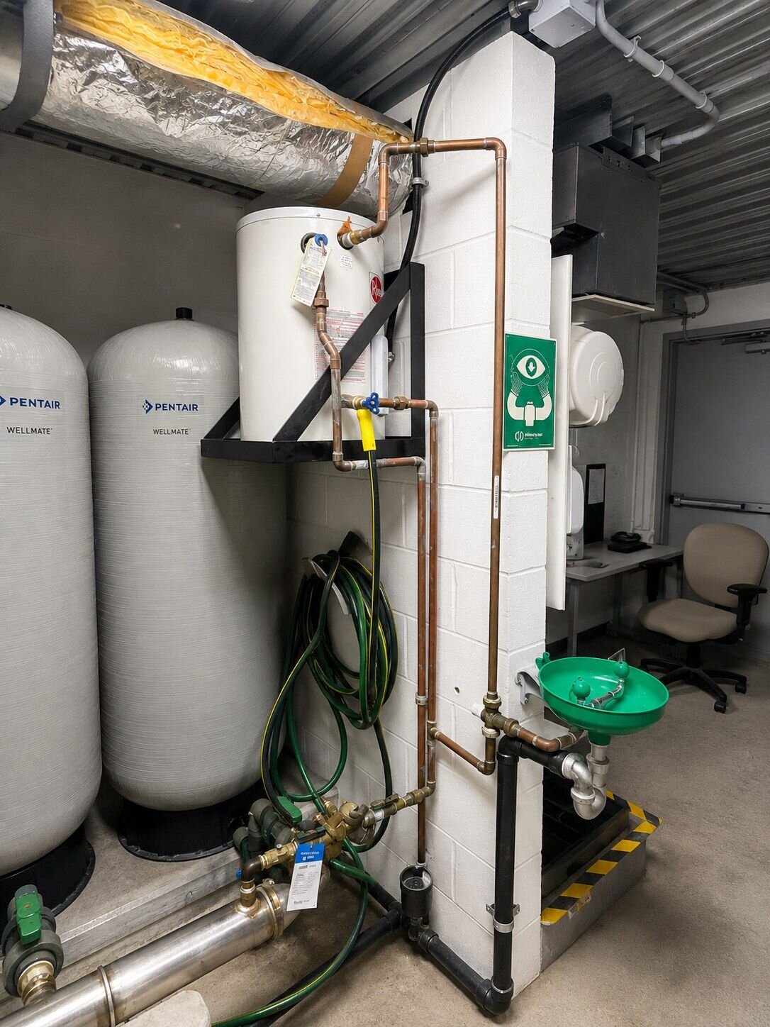 Pressure tanks and water heater in an operating facility, beside an eyewash station