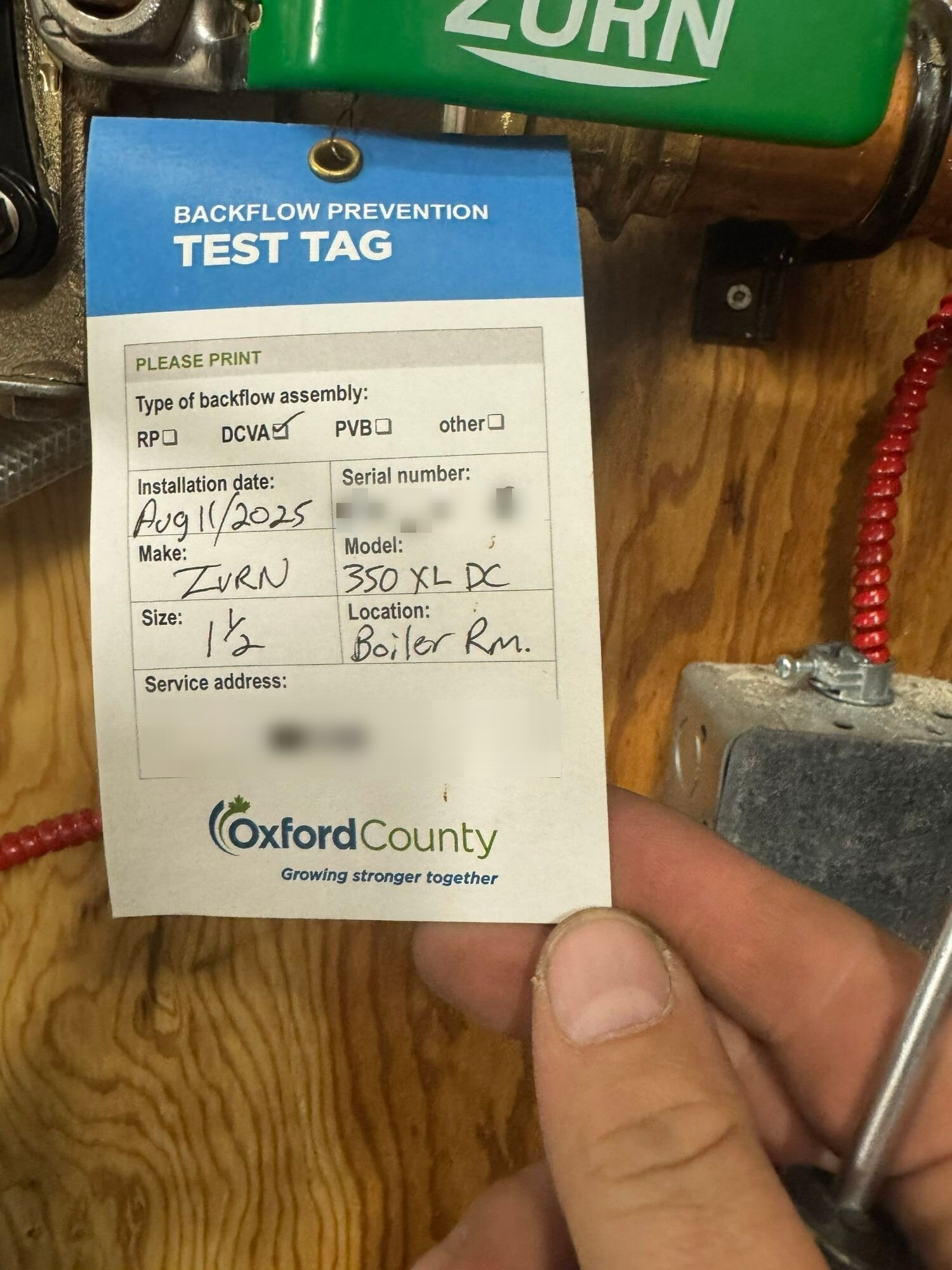 Einwechter plumber holding a backflow test tag at the device | Backflow testing, Kitchener-Waterloo Einwechter plumber holding a backflow test tag at the device, Kitchener-Waterloo