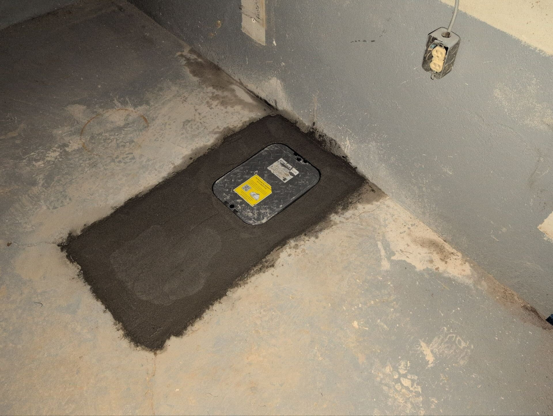 Backwater valve access lid in a patched basement floor