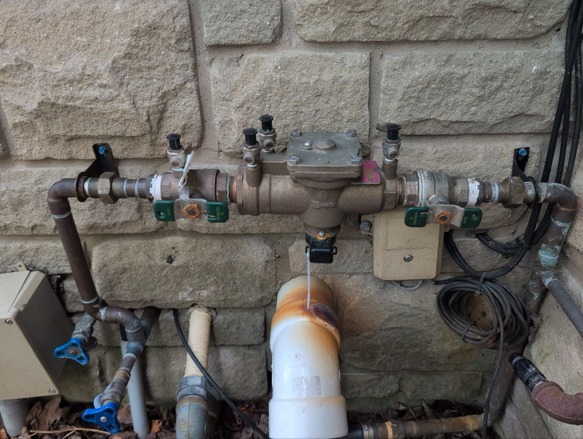 Backflow preventer on an irrigation line against a stone wall | Backflow testing, Kitchener-Waterloo Backflow preventer on an irrigation line against a stone wall – backflow testing, Einwechter Plumbing & Heating, Kitchener-Waterloo